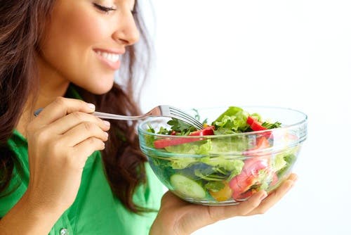 mujer que come ensalada para el estreñimiento causado por estrés