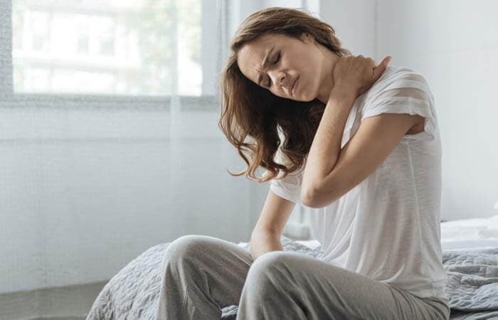 Mujer levantándose de la cama con torticolis