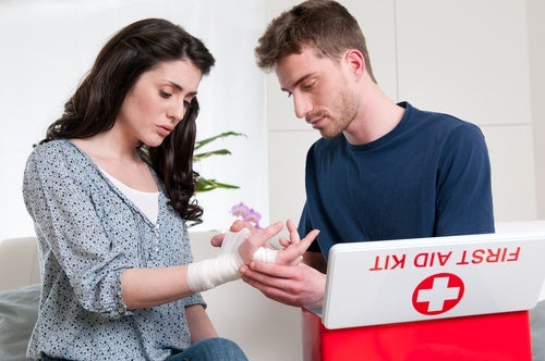 Chico curando la mano a chica junto a un botiquín de primeros auxilios
