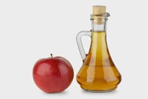 Vinagre de manzana en frasco junto a una manzana roja