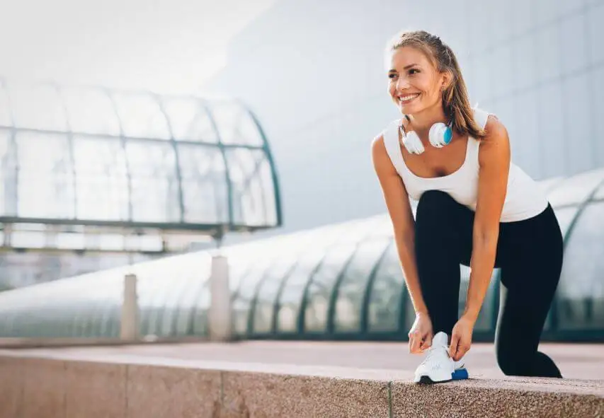 Chica atándose los zapatos a punto de correr.