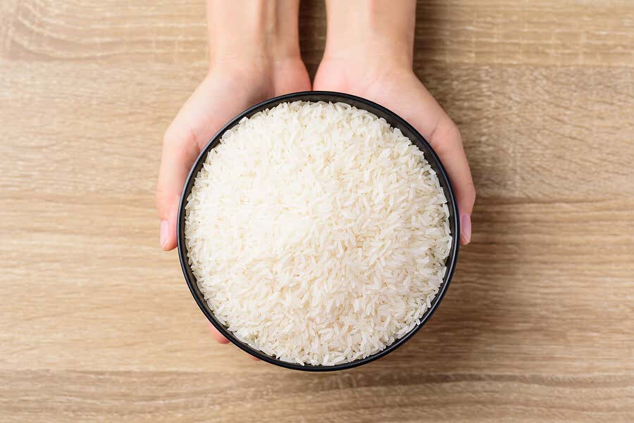 Manos sujetando un bol de arroz blanco.