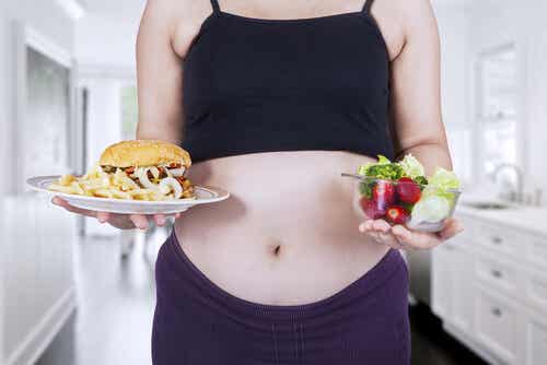 Mujer embarazada entre comida buena o mala.