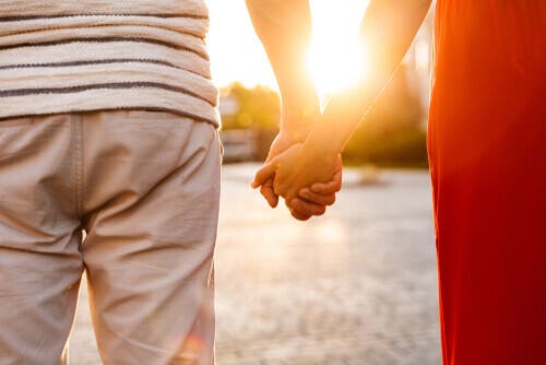 Pareja caminando tomada de la mano al atardecer.
