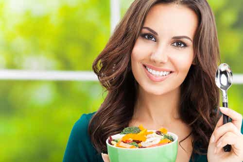 Mujer con un bol de frutas y verduras. Alimentación equilibrada entre los hábitos saludables para potenciar la fertilidad.
