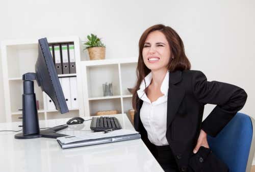 Mujer con dolor de espalda por estar sentada frente al ordenador