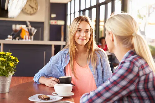 Dos mujeres hablando mientras toman café.