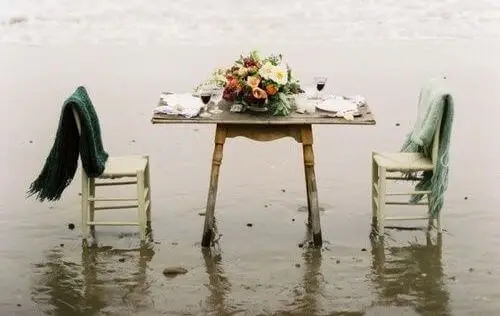 Mesa en la playa con sillas vacías.
