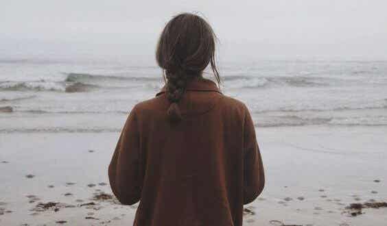 Mujer de espaldas en una playa en invierno.