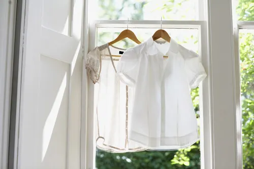 Ropa tendida en el marco de una ventana para humidificar el ambiente.