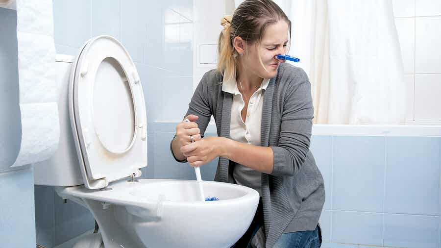 Mujer limpiando inodoro con mal olor.