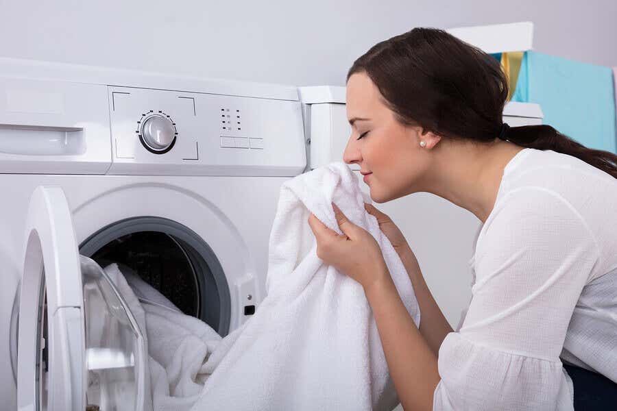 Mujer oliendo toallas limpias con suavizante natural.