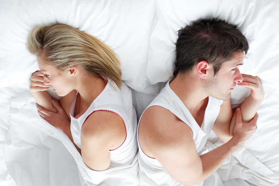 Pareja distanciada en la cama.