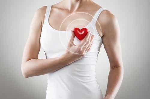 Kvinde holder plastikhjerte foran sig eget hjerte