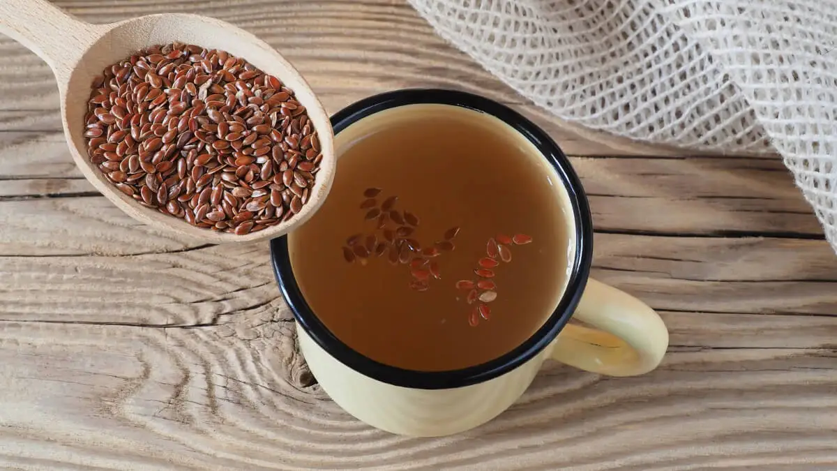 Agua de linaza en una taza y una cuchara con esta semilla.