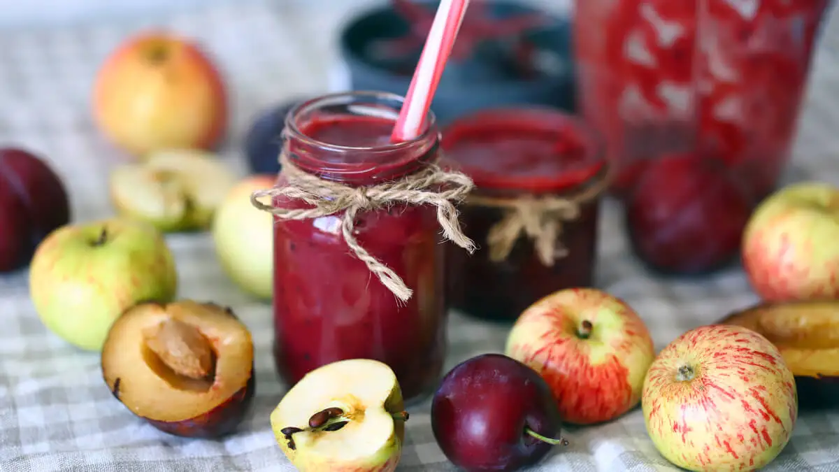 Un jugo para depurar el estómago, con manzanas, ciruelas y duraznos alrededor.