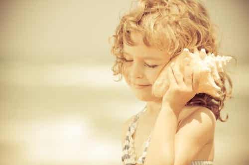 Et barn som lytter til et skjell.