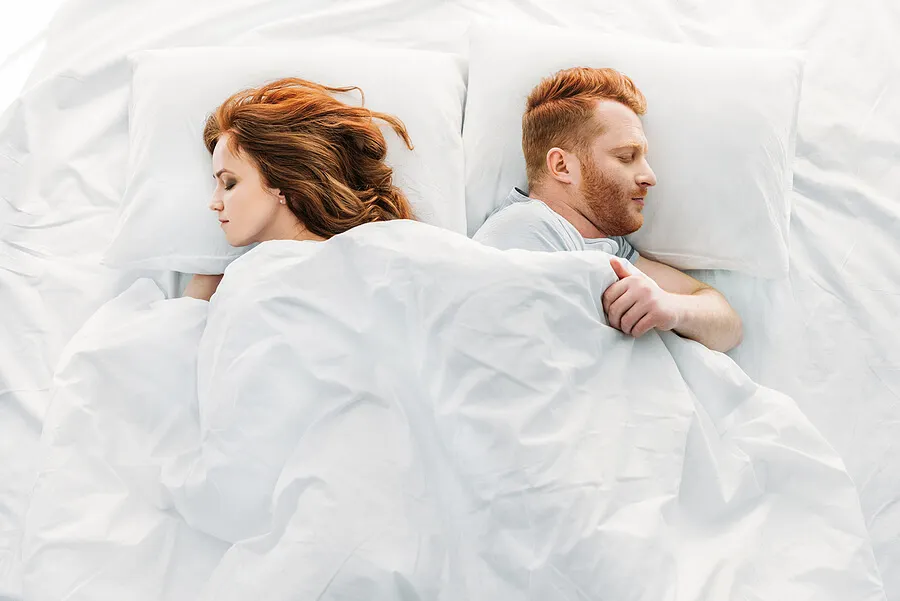 Pareja en la cama durmiendo de lado.