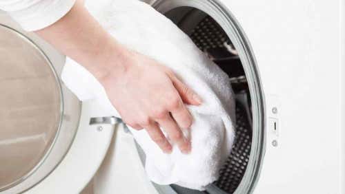 A person putting a towel in a washing machine.