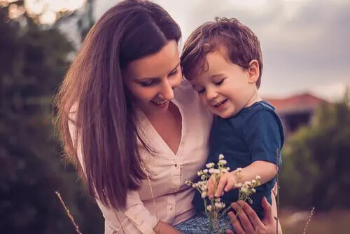 Madre-cogiendo-a-su-hijo-en-brazos-mientras-ven-una-flor