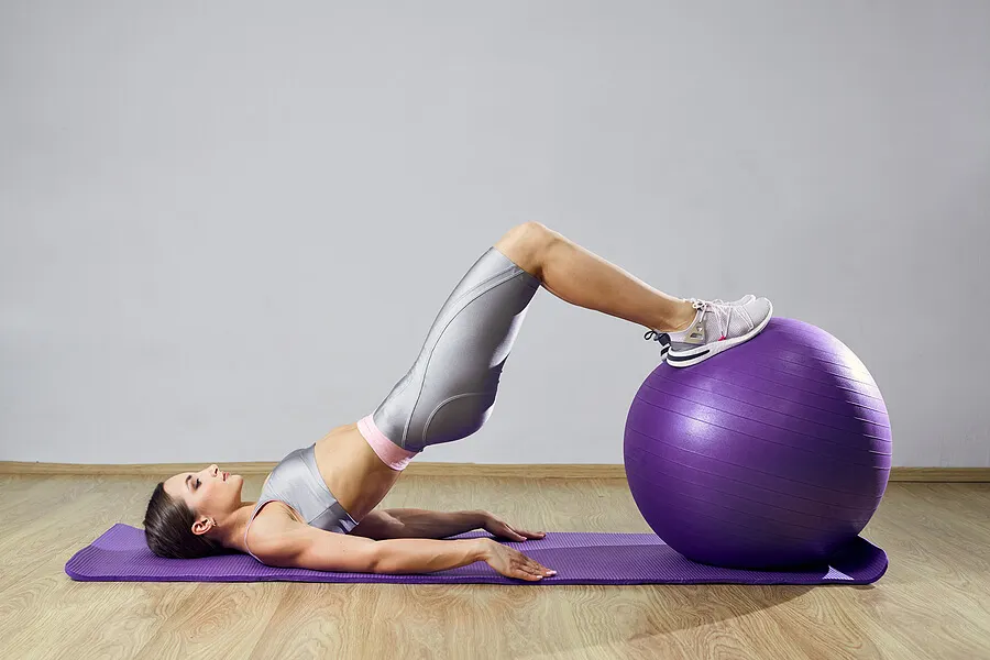 Chica haciendo pilates con un balón suizo