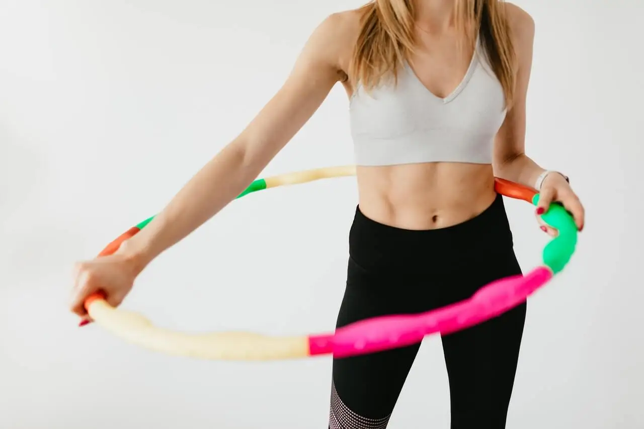 a woman using weighted hula hoops