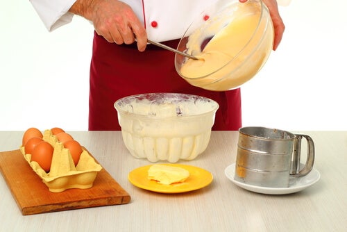 Cocinero batiendo crema en un bol con demás ingredientes para elaborarla en la mesa.