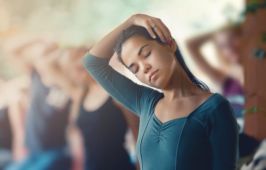 Chica realizando un estiramiento de cuello en clase de yoga.