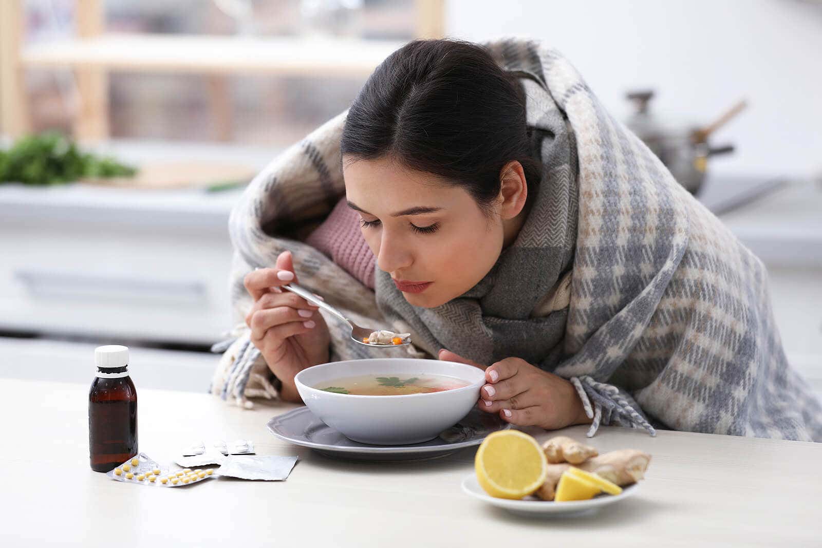 Mulher com gripe tomando uma sopa.