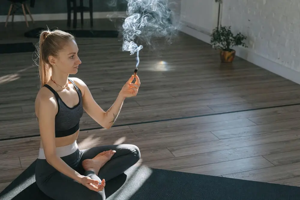 Salbei-Räuchern - Frau sitzt im Yogasitz und räuchert