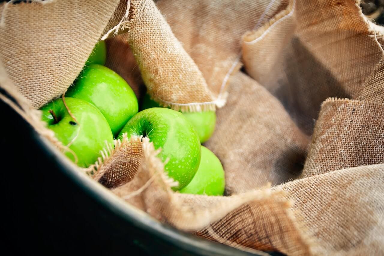 Manzanas verdes en una cesta con tela.