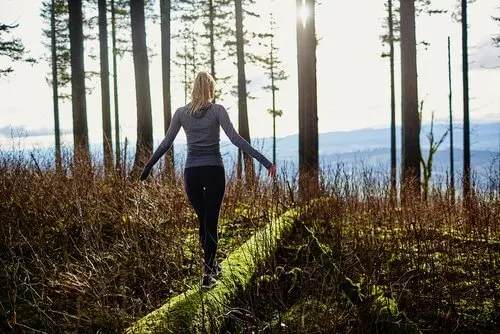 Frau balanciert auf einem umgefallenen Baum
