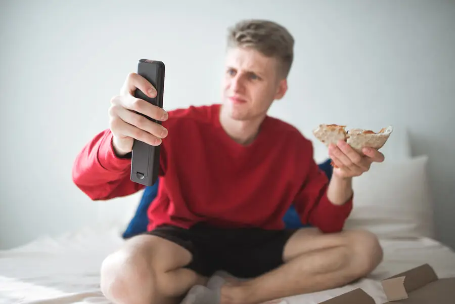 Hombre sujetando mando en una mano y bocata en otra.