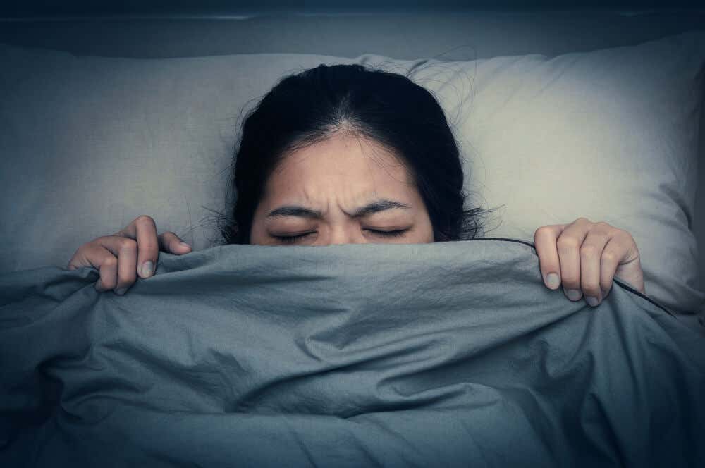 Albtraumstörung - verängstigte Frau unter der Bettdecke