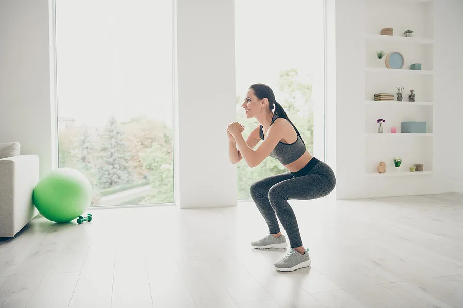 Mujer haciendo sentadillas en casa.