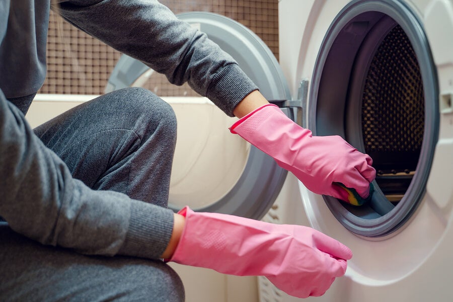 Mulher limpa a máquina de lavar para remover odores.