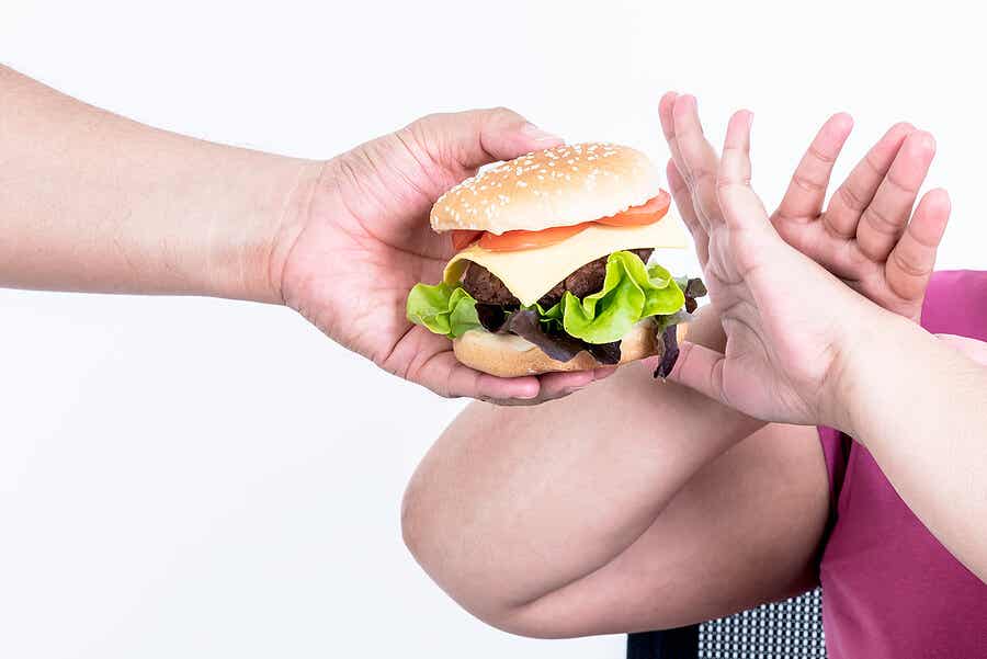 Persona obesa rechazando hamburguesa
