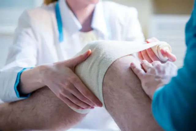 Sanitaria aplicando un vendaje en la rodilla.