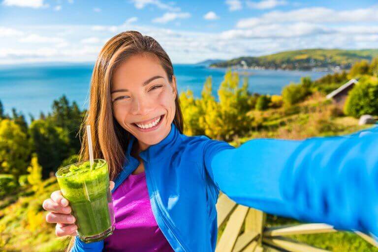 Chica sonriendo con un batido verde.