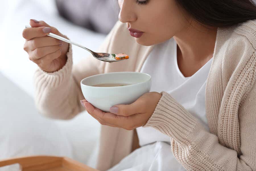 Mujer comiendo cuenco de sopa.
