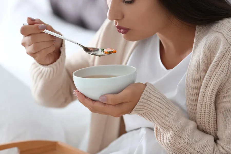 Mujer comiendo cuenco de sopa.