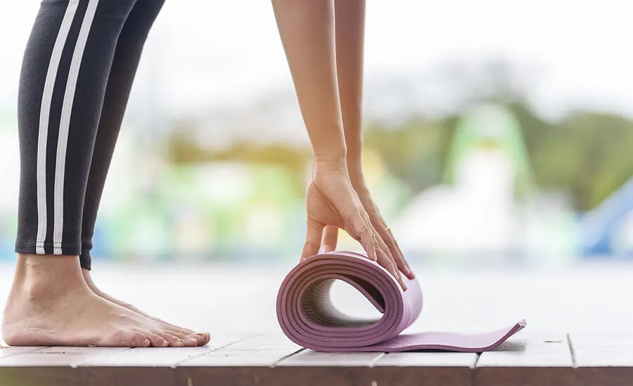 Mujer desplegando esterilla de yoga