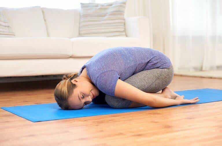 Mujer realizando la postura del niño en sesión de yoga.
