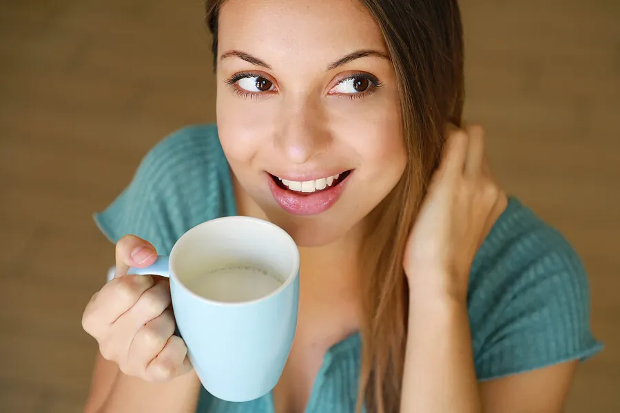 Mujer bebiendo leche en una taza.