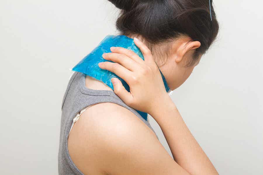 Mujer colocándose una compresa fría en el cuello para aliviar dolor.