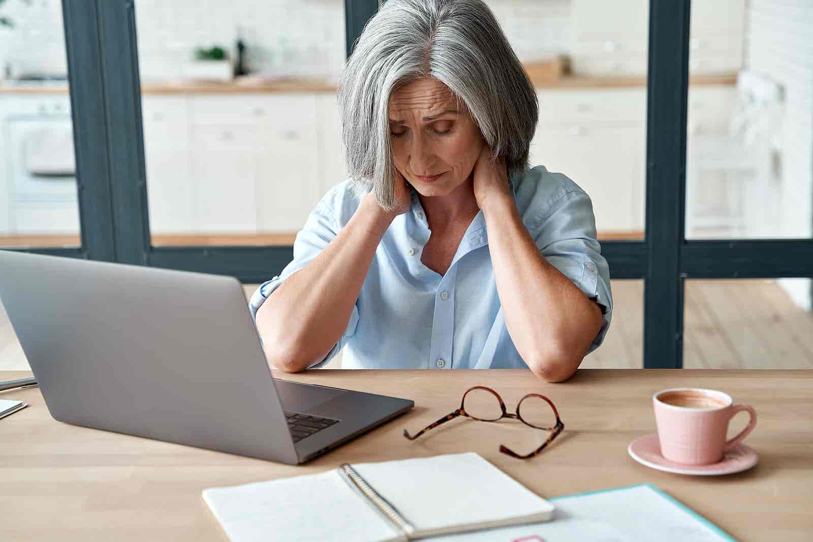 Mujer con dolor de cuello por mala postura frente al ordenador.