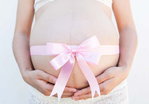 Barriga de embarazada con un lazo rosa alrededor
