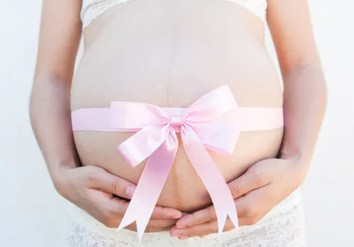 Barriga de embarazada con un lazo rosa alrededor