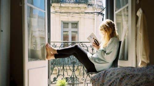 Mujer leyendo en la ventana.