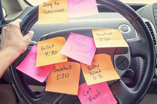 Persona en el coche con el volante lleno de notas escritas con las cosas pendientes de hacer
